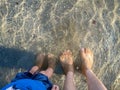 Father and son feet on shallow beach water Royalty Free Stock Photo