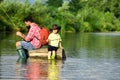 Father and Son fishing - Family Time Together. Happy father and son fishing in river holding fishing rods.