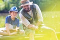 Father and son fishing in Lake while sitting on pier Royalty Free Stock Photo