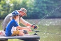 Father and son fishing in Lake while sitting on pier Royalty Free Stock Photo