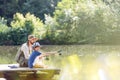 Father and son fishing in lake while sitting on pier Royalty Free Stock Photo