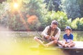 Father and son fishing in Lake while sitting on pier Royalty Free Stock Photo