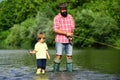 Father and son fishing and relaxing while enjoying hobby. Anglers. Fishermen father and son fishing in a river with a