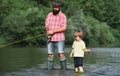 Father and son fishing and relaxing while enjoying hobby. Anglers. Fishermen father and son fishing in a river with a