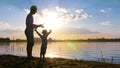 Father and son fishing on the river bank in the rays of sunset Royalty Free Stock Photo