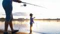 Father and son fishing on the river bank at sunset Royalty Free Stock Photo