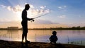 Father and son fishing on the shore of the river in the rays of sunset Royalty Free Stock Photo