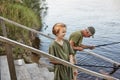 Father and son fishing together, standing on wooden stairs leading to water, grandson with his grandpa having fun in open air, Royalty Free Stock Photo