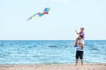 Father with son flying kite near sea Royalty Free Stock Photo