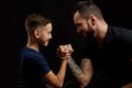 Father and son during friendly arm wrestling competition on black Royalty Free Stock Photo