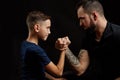 Father and son during friendly arm wrestling competition on black Royalty Free Stock Photo