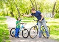 Father and son give high five while cycling in the park Royalty Free Stock Photo