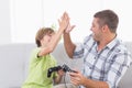 Father and son giving high-five while playing video game Royalty Free Stock Photo