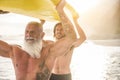 Father and son going to surf on tropical beach - Family people having fun doing extreme sport - Joyful elderly and healthy