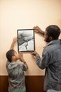 Father and son hanging art on wall Royalty Free Stock Photo