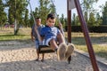 Father and son having fun playing with the swing in a park. Royalty Free Stock Photo