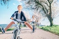 Father and son having fun spreading wide legs and screaming when riding bicycles on country road under blossom trees. Healthy