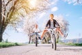 Father and son having fun when riding bicycles on country road under blossom trees. Healthy sporty lifestyle concept image