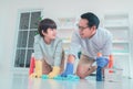 Father and son having fun wiping and cleaning the floor together with cleaning liquid agent and colorful towels for family