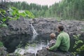 Father and son hikers travellers sitting near mountain waterfall. Peaceful and calmness scenic view. Active family outdoors Royalty Free Stock Photo