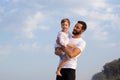 Father with son in his arms walking on a tropical beach