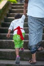 Father and son hold hands and climb the stairs. Indonesian culture. Island of Bali. Close up