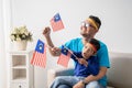 Father and son holding malaysian flag together while watching soccer match Royalty Free Stock Photo