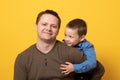 Father and son hugging on yellow background. Portrait of a dad with a baby boy smiling and hugging. Family concept Royalty Free Stock Photo