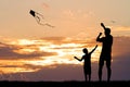 Father and son with kite at sunset