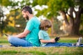 Father and son with laptop in park. Daddy teaches child use modern technology. Distance learning lesson. School