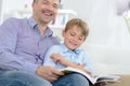 Father and son laughing while reading book Royalty Free Stock Photo