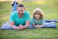 Father and son laying on grass in park. People having fun outdoors. Concept of happy vacation and friendly family. Royalty Free Stock Photo