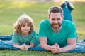 Father and son laying on grass in park. People having fun outdoors. Concept of happy vacation and friendly family. Royalty Free Stock Photo