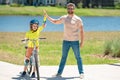 Father and son learning to ride a bicycle having fun together at Fathers day. Father teaching his son cycling on bike in Royalty Free Stock Photo