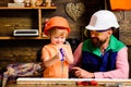 Father and son learning use carpenter tools. Boy with dad building wooden house together. Fatherhood concept.