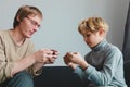 Father and son looking at mobile phones at home, family playing games Royalty Free Stock Photo