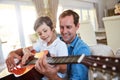 Father and son musical fun. a father and his young son sitting together in the living room at home playing guitar. Royalty Free Stock Photo