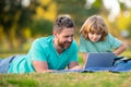 Father and son online learning. Concept of friendly family. Kid with a laptop outdoors in the summer. Child in a park on Royalty Free Stock Photo