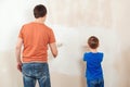 Father and son painting a wall. Happy family renovating their new home Royalty Free Stock Photo