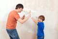 Father and son painting a wall. Young family painting house wall Royalty Free Stock Photo