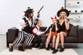 father and son in pirates costumes scaring mother and daughter on sofa