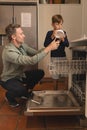 Father and son placing bowl in dishwasher in the kitchen Royalty Free Stock Photo