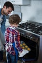 Father and son placing cupcakes tray in oven Royalty Free Stock Photo