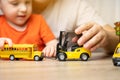 Father and son play with cars. Spending time with children. The concept of a happy childhood. School bus and forklift. Close up. Royalty Free Stock Photo