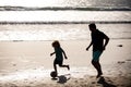 Father and son play soccer or football on the beach. Dad and child playing outdoor. Childhood and parenting concept. Royalty Free Stock Photo