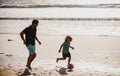 Father and son play soccer or football on the beach. Dad and child playing outdoor. Childhood and parenting concept. Royalty Free Stock Photo