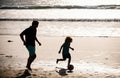 Father and son play soccer or football on the beach. Dad and child playing outdoor. Childhood and parenting concept. Royalty Free Stock Photo