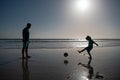 Father and son play soccer or football on the beach. Daddy with kid boy playing on a summer day. Royalty Free Stock Photo