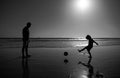 Father and son play soccer or football on the beach. Daddy with kid boy playing on a summer day. Royalty Free Stock Photo