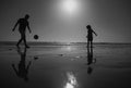 Father and son play soccer or football on the beach, silhouette on sunset. Dad and child having fun outdoors. Royalty Free Stock Photo